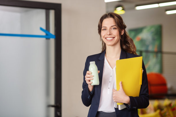 苗条的年轻女子，带着一瓶牛奶和文件夹。图片下载
