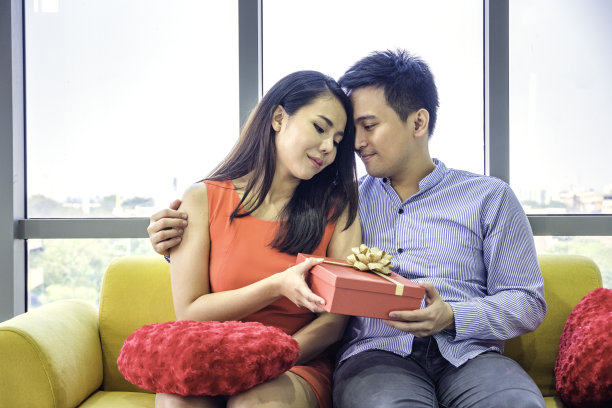 亚洲男人在客厅给女朋友惊喜的礼物。情人节或生日当天，新冠肺炎疫情隔离结束后的情侣共同庆祝。回归正常的生活方式。图片下载