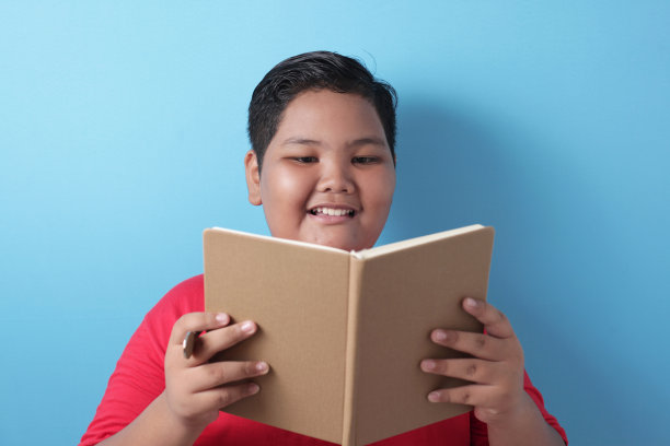 胖胖的亚洲男孩在看书时快乐地微笑图片下载