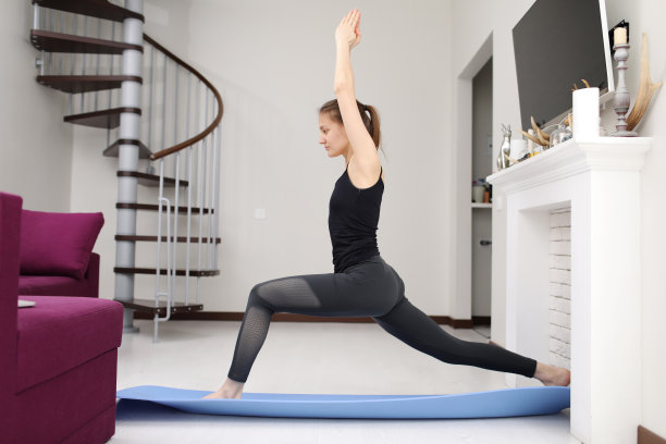 做瑜伽练习。身材苗条的年轻女子穿着运动服在家进行健身。图片下载