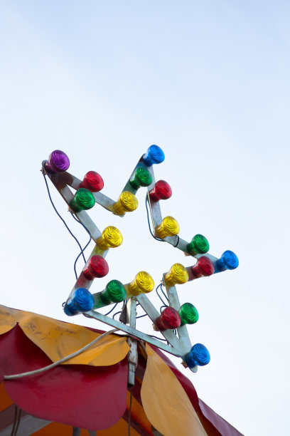 多色灯泡在旋转木马顶部照明。星形金属框架上的彩色灯泡。垂直格式图片下载