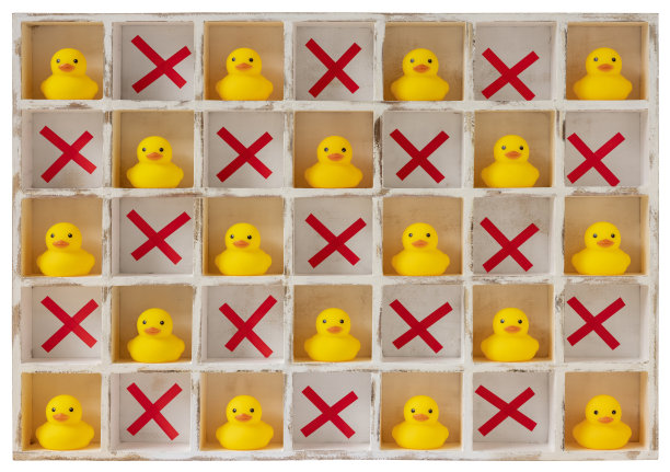 许多单独的黄色橡皮鸭被安置在白色的木制隔间或鸽子洞里，用一个标有十字的空洞彼此隔开，仿佛被隔离、封锁或隔离。孤立在一个白色的背景，剪切路径包括。图片下载