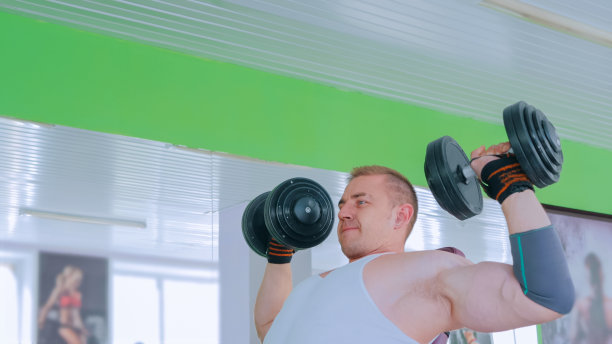 健壮的年轻人在健身房举哑铃图片下载