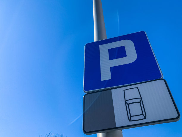 蓝色的天空下，铁柱上的停车路标。图片下载