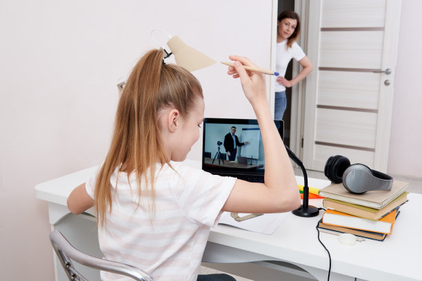 母亲看着她的女儿在家里用笔记本电脑做作业图片下载