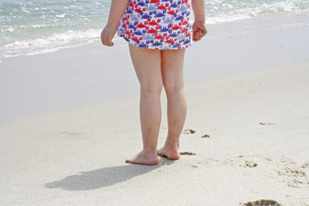 孩子的腿站在沙滩上。图片下载