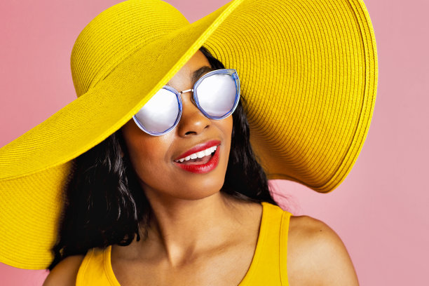 一个年轻的微笑女人的近距离肖像与夏天的帽子和太阳镜图片下载