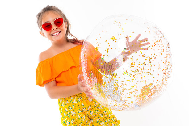 照片中的白人女孩戴着太阳镜，拿着一个巨大的可充气的伤口颜色的球，孤立在白色的背景上图片下载