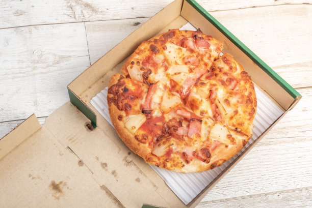 披萨，卡哇伊，火腿，奶酪，撒在纸盒里，保留了绿糖帕尔马干酪的味道，剃了奶酪，意大利披萨和特殊的装饰在木地板上图片下载
