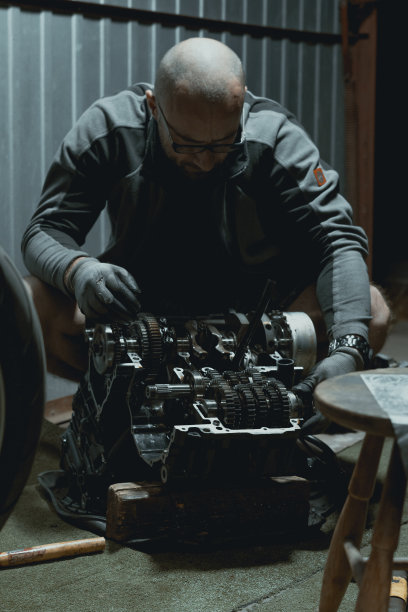 在车库里修理摩托车引擎的人。图片下载