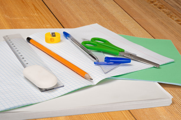 学校文具如方格笔记本，剪刀，铅笔带橡皮擦，钢笔带帽，尺子，橡皮擦和卷笔刀。在木桌上。有选择性的重点。回到学校概念照片。图片下载