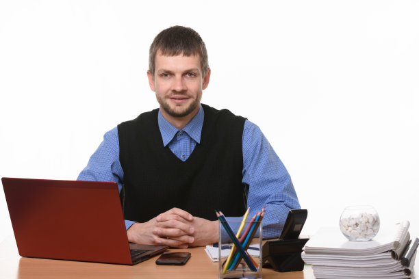 一个办公室职员坐在一张桌子旁，抓着他的手指，看着画框图片下载