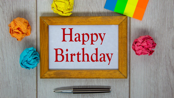 木制框架与“生日快乐”在美丽的木制桌子，彩色纸，金属笔。的概念。图片下载
