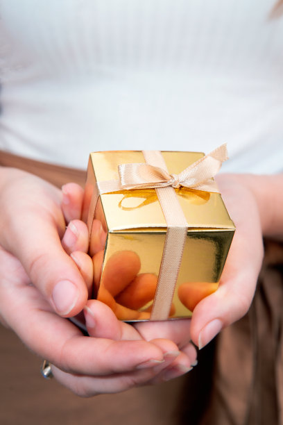 女人的手拿着金礼盒，节日礼物，生日，圣诞节，父亲或母亲的，情人节特写图片下载