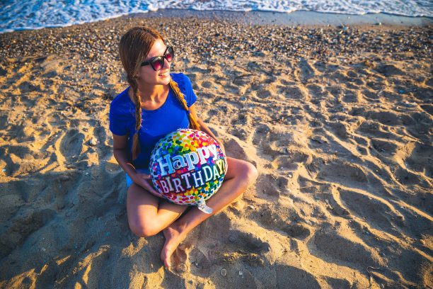 坐在海滩上拿着生日气球的女人图片下载