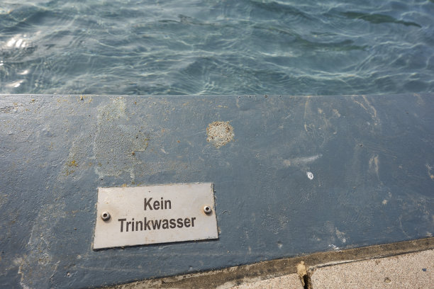 长方形金属标志贴在地板上。(德语单词Kein Trinkwasser的翻译:没有饮用水)肮脏的蓝色环境，池塘是可见的。德国。图片下载