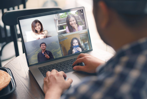 年轻人在视频会议上谈论自由撰稿人报道。亚洲团队使用笔记本电脑和平板电脑进行在线视频会议。在咖啡店工作，远程工作和社会隔离。图片下载