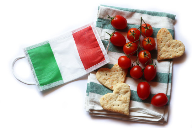 面部保护面具的意大利国旗形状的心饼干和红色的西红柿孤立在白色图片下载