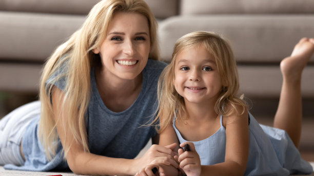 母亲娇小的女儿躺在温暖的地板上画画享受闲暇图片下载