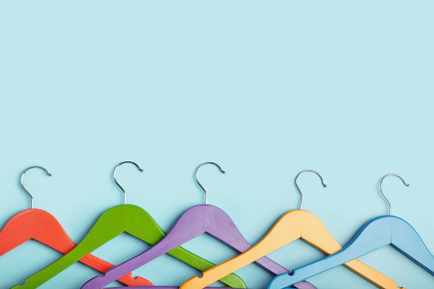 5个儿童衣架，用来挂五颜六色的衣服。蓝色背景。图片下载