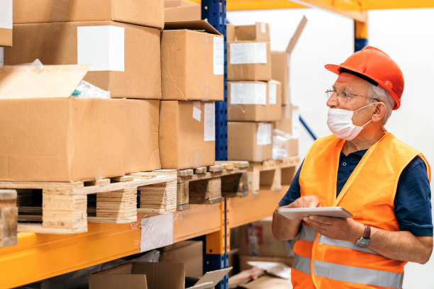 高级经理戴着防护口罩，使用数码平板电脑，在仓库工作图片下载