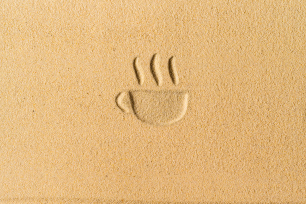 在热带海滩的沙子上画的复古咖啡杯。平躺图片下载