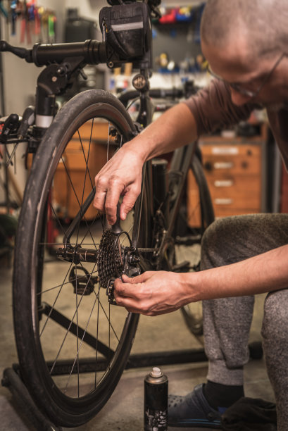 年轻人在旧车库修理公路自行车。图片下载