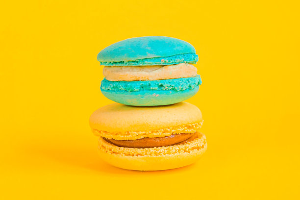 甜杏仁，彩色独角兽，蓝色，黄色杏仁饼或杏仁饼甜点孤立在时尚的黄色，现代时尚的背景。法国甜的饼干。最小的食品烘焙概念拷贝空间图片下载