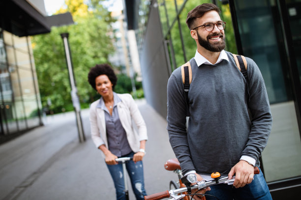 快乐的商务人士上班骑自行车，电动踏板车在城市街道上图片下载