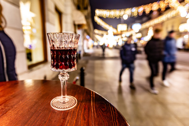 街道上的木桌上放着一杯红酒，背景是模糊的灯光。水平方向图片下载