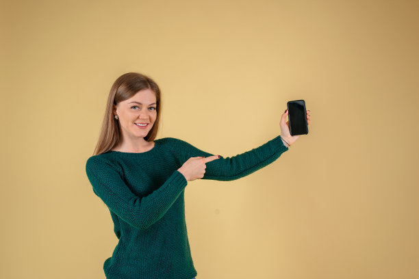 可爱友好的欧洲时尚博主在口袋里牵手，黄色背景上显示智能手机广告图片下载