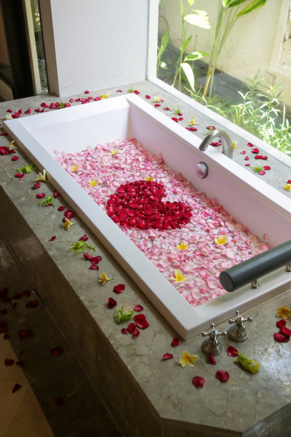 充满玫瑰和鸡蛋花花瓣的浴缸，周末水疗，健康，身体护理和美容概念图片下载