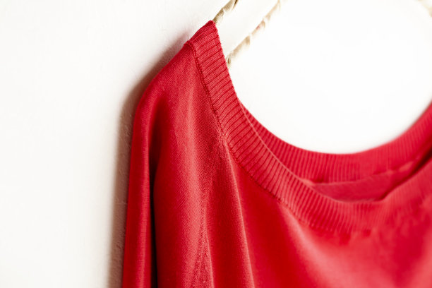 挂在衣架上以白色为背景的红色裁剪的缝纫或编织。图片下载