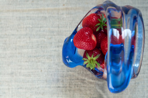 灰色背景下的玻璃花瓶里装着成熟的红草莓图片下载