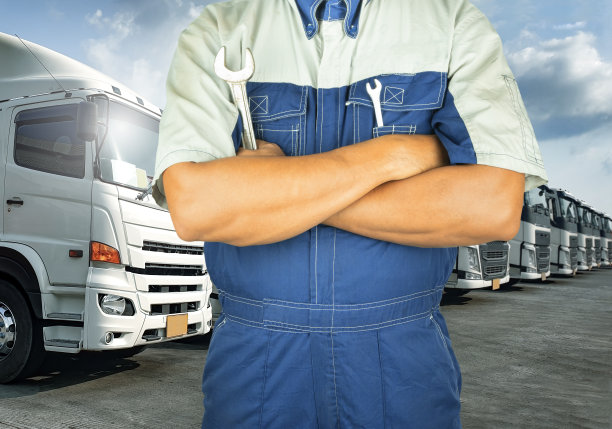 专业的汽车技师拿着扳手与半卡车在停车场。图片下载