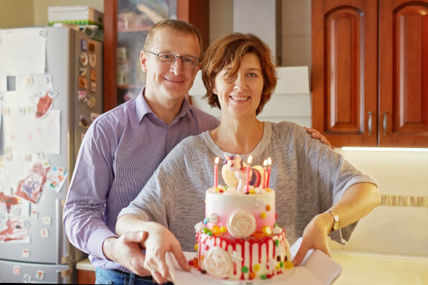 丈夫和妻子手里拿着一个插着蜡烛的蛋糕。图片下载