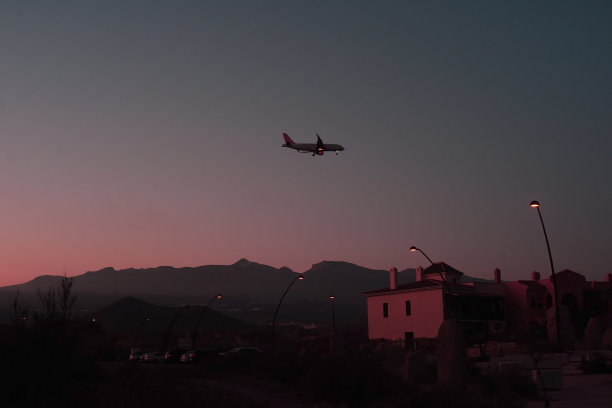 一架飞机在粉红色的夕阳下起飞的漂亮的夜景。飞机飞到降落，起飞。美丽的日落，夜航，非常早的航班。神秘、神秘、嘈杂的照片;图片下载