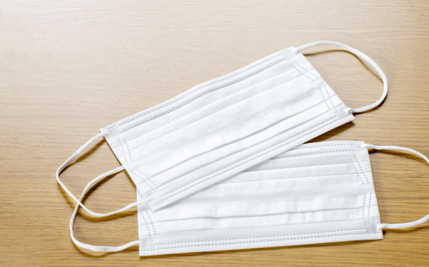 简单的白色空气保护口罩上的颜色表面上的木制背景。一次性外科口罩盖住口鼻。图片下载