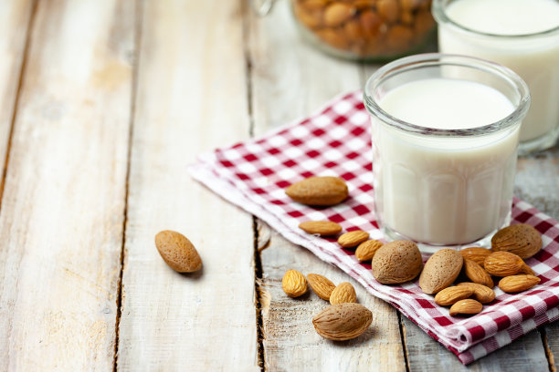 新鲜有机素食杏仁奶。素食者的蛋白质替代来源。原料生杏仁，去皮和未去皮。健康生活方式的概念。特写，白色背景，拷贝空间图片下载