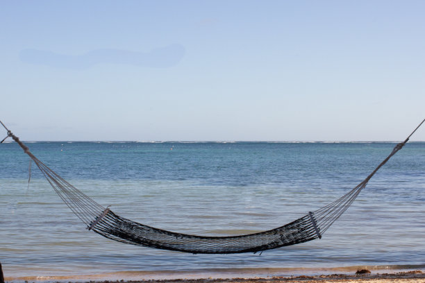 吊床悬挂在平静的大海前面图片下载