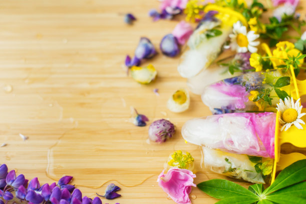 花冰棍和新鲜的夏季花与文本空间。彩色的野花在融化的冰心和冰棒木制的背景。你好,夏天的概念。创意图片图片下载