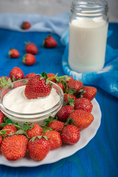 盘子里装着熟透多汁的草莓和装满牛奶的罐子图片下载