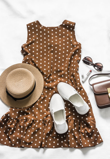 夏季棕色圆点无袖连衣裙，白色皮革运动鞋，斜挎包，太阳镜，口红和帽子在一个光的背景，俯视图图片下载