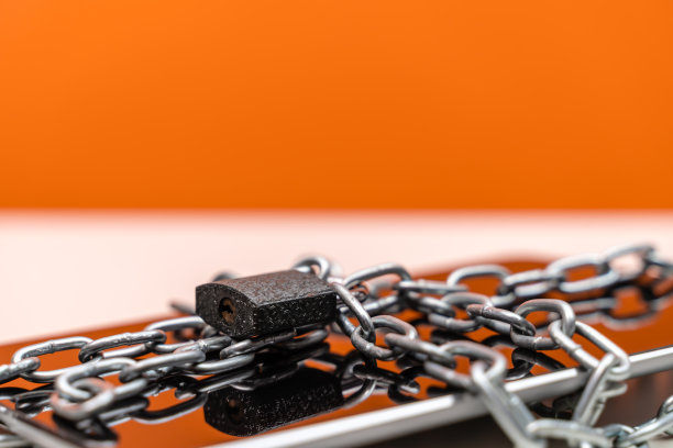 数字平板电脑与挂锁和链在橙色的背景图片下载