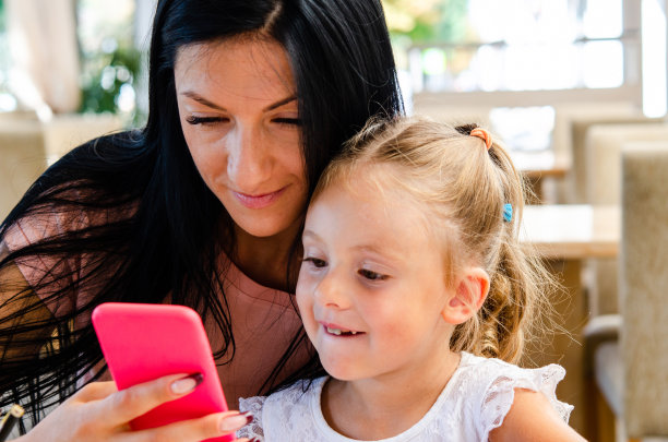 一个微笑的女孩在用智能手机和一个可爱的女孩自拍图片下载