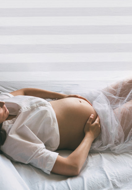一名孕妇躺在床上，腹部露在外面图片下载