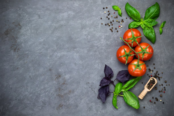 西红柿在树枝上和薄片上，罗勒叶在灰色的表面上。配料:蔬菜，香料，绿叶蔬菜。背景。菜单、菜谱图片下载