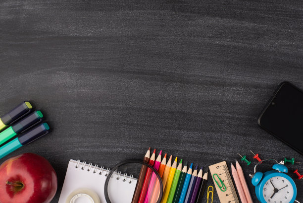 技术与学校理念。上面俯瞰智能手机苹果和彩色文具孤立在黑板与copyspace的照片图片下载