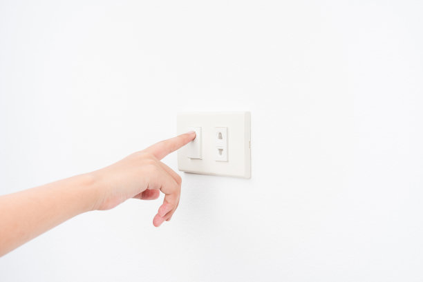手按白墙背景上的电子灯开关图片下载