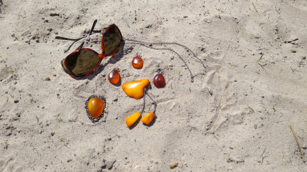 琥珀色的首饰，沙滩上的太阳镜。图片下载